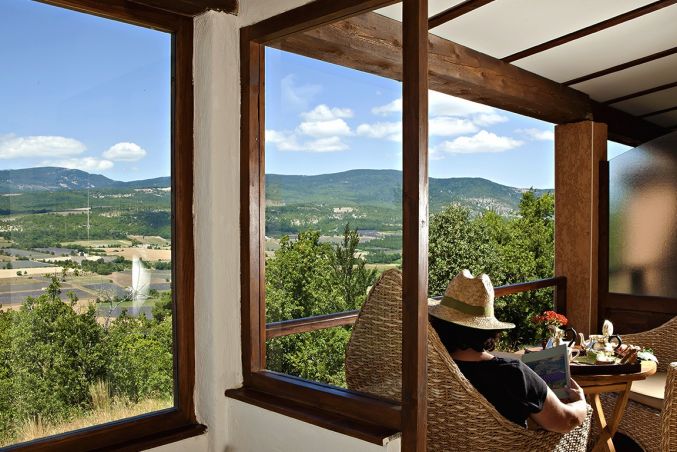 A person reading on the balcony of the Provence Asie suite at the 4-star Domaine du Val de Sault hotel in the Luberon.